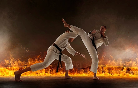 Two karate athletes engaged in an intense sparring match with a powerful high kick surrounded by flames and cinematic smoke effects.